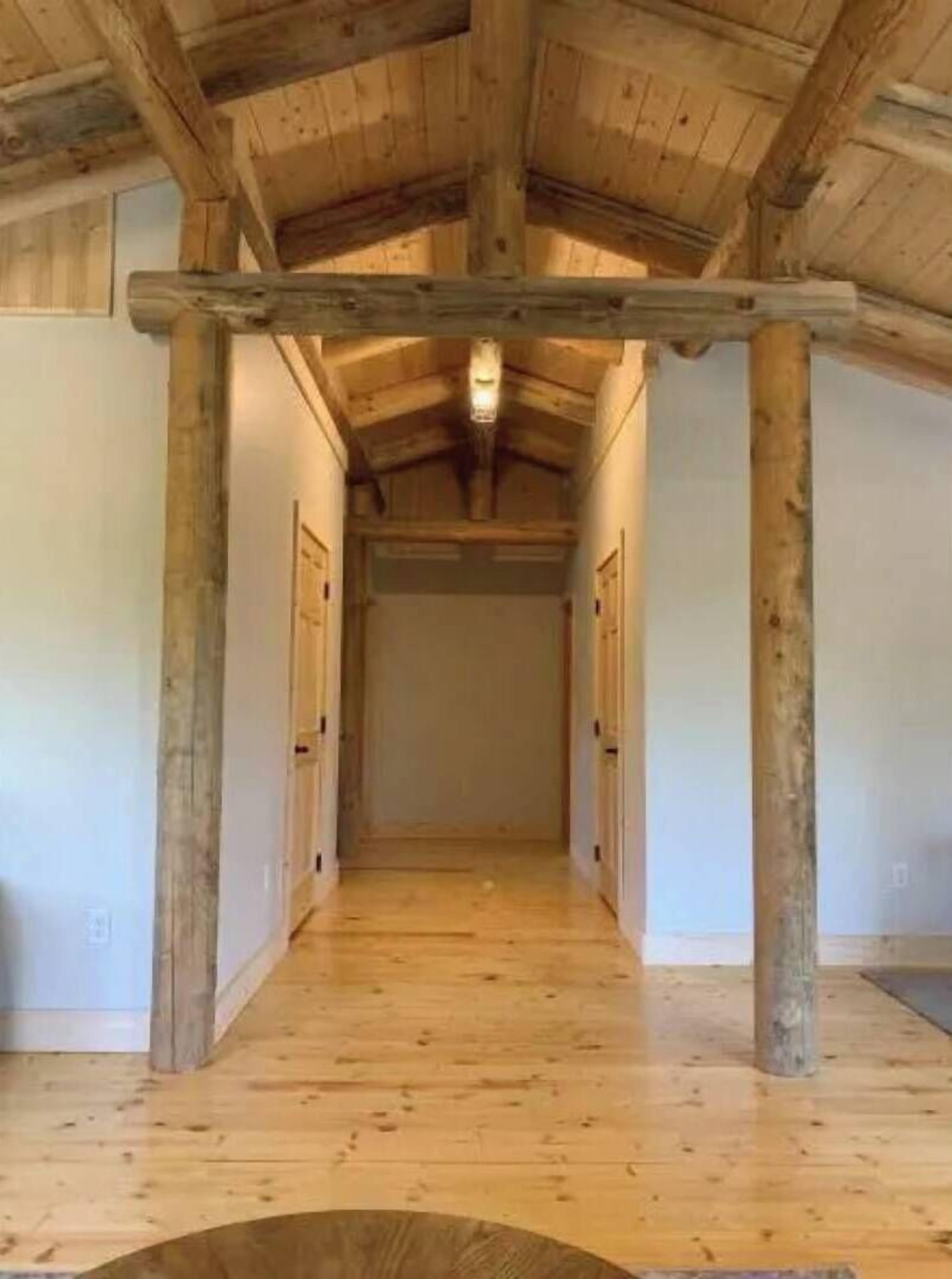 Un couloir avec des poutres en bois, un plancher en bois et un luminaire au plafond.