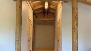 Een gang met houten balken, een houten vloer en een lamp aan het plafond.