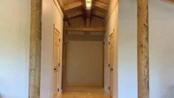 Un couloir avec des poutres en bois, un plancher en bois et un luminaire au plafond.