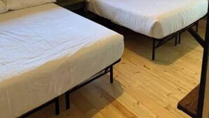 Een chalet met twee bedden, houten wanden en een raam.