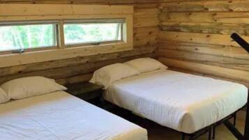 A cabin with two beds, wooden walls, and a window.