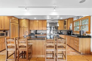 Eine Küche mit Holzausstattung, Edelstahlgeräten und einer zentralen Kochinsel mit Barhocker.