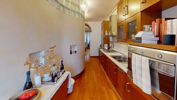 Una cocina con armarios de madera, horno de acero inoxidable y encimera con diversos objetos.