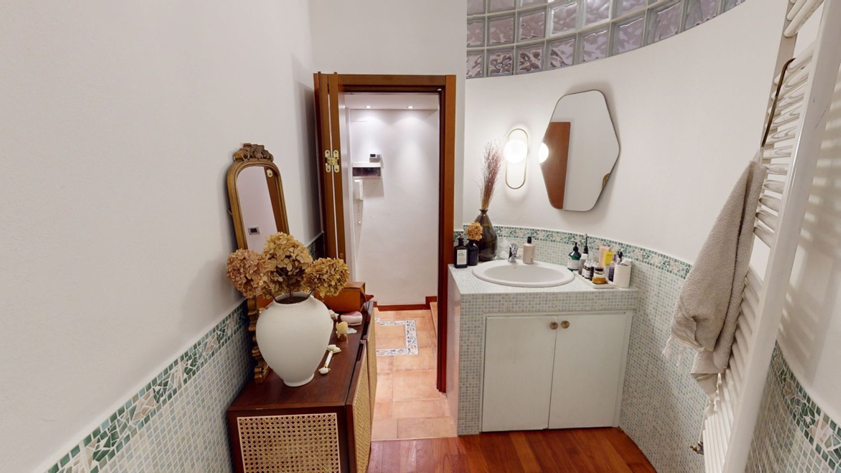 Une salle de bain avec un meuble-lavabo en bois, un grand miroir, un lavabo blanc et un porte-serviettes.