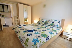 Ein Schlafzimmer mit Bett, Nachttisch, Lampe und Kleiderschrank.