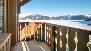 Ein Holzbalkon mit Blick auf schneebedeckte Berge und einen klaren Himmel.