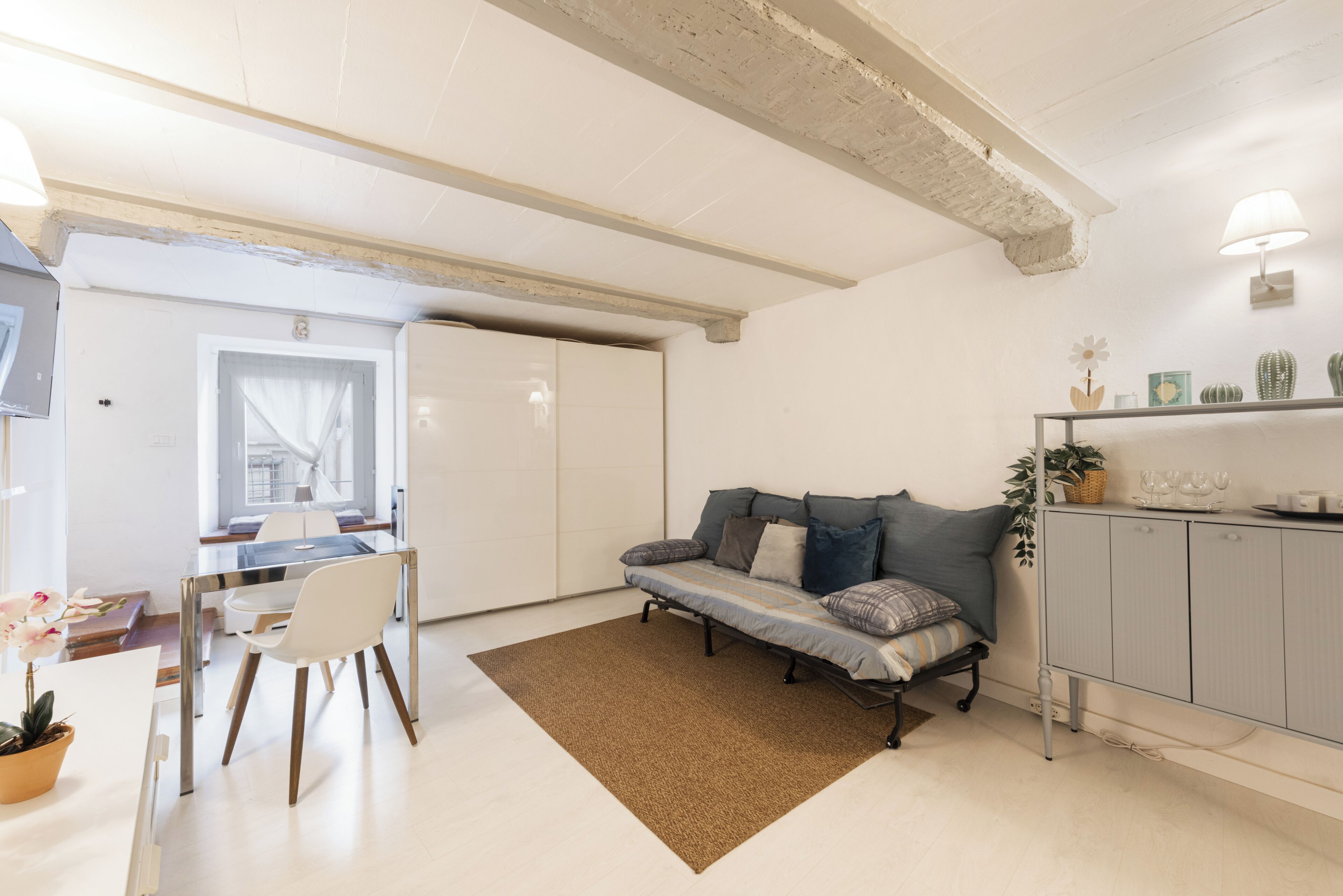 Una sala de estar moderna con un sofá, una mesa de comedor, sillas y una cocina con gabinete y encimera.