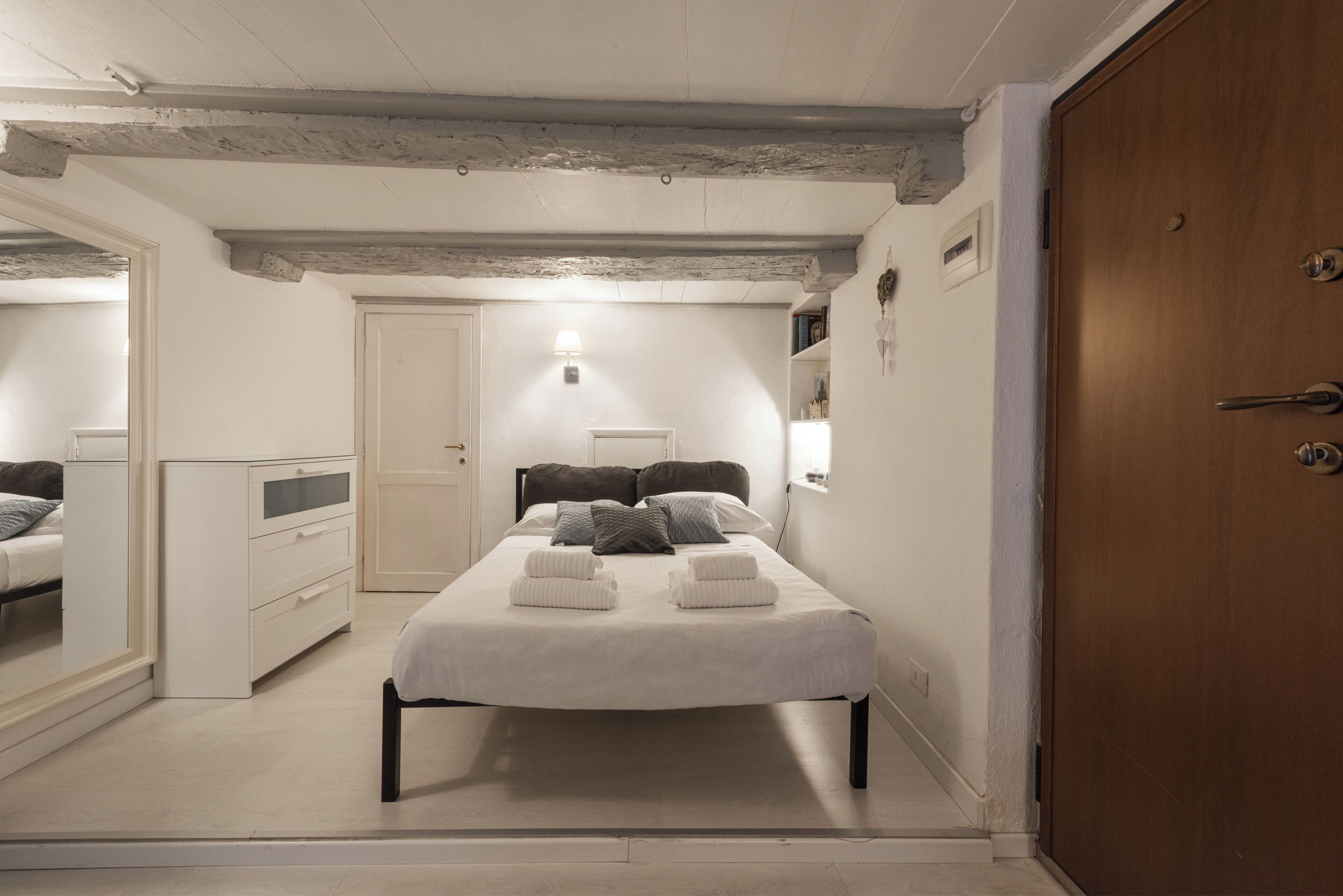 Un dormitorio con cama, mesitas de noche, armario y espejo.