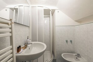 Ein Badezimmer mit Dusche, zwei Waschbecken, einem Spiegel und einem Handtuchhalter.