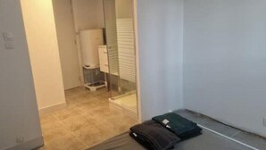 A narrow hallway with a glass door leading to a bathroom. A suitcase is placed on the floor near the door. - T2 Fully Equipped 4 Sleeps - Comfort and Proximity to Amenities (Réalmont)