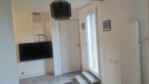 A hallway with a door, a window, and a mounted air conditioner. - T2 Fully Equipped 4 Sleeps - Comfort and Proximity to Amenities (Réalmont)