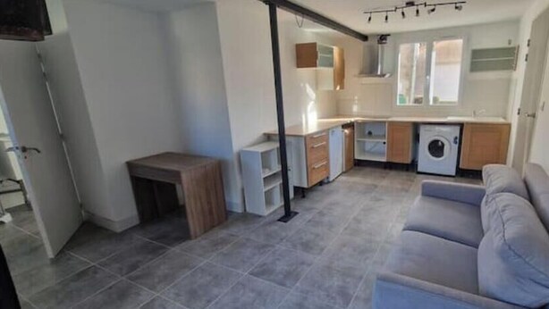 A compact living space with a kitchenette, a sofa, and a small table. - T2 Fully Equipped 4 Sleeps - Comfort and Proximity to Amenities (Réalmont)