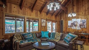 A wooden interior with a leather sectional sofa, a round coffee table, and a chandelier.