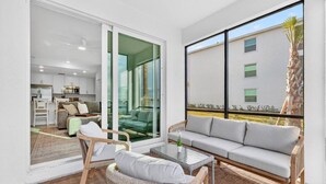 Un soggiorno moderno con un divano, poltrone e una porta vetrata che dà su un balcone.
