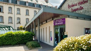 Ein Hotel mit Eingangsbereich, einer Rezeption, einem überdachten Gang und einer Steinfassade.