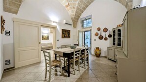 A dining area with a table and chairs, a kitchen with cabinets, and a stone ceiling. - Live the History: The timeless charm of an Ancient Dwelling in the heart of Maglie (Maglie)