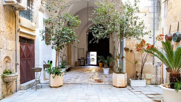A courtyard with stone flooring, potted plants, and a central archway. - Live the History: The timeless charm of an Ancient Dwelling in the heart of Maglie (Maglie)