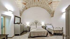 A bedroom with a stone ceiling, two beds, a dresser, and a mirror. - Live the History: The timeless charm of an Ancient Dwelling in the heart of Maglie (Maglie)