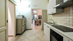 A kitchen with a tiled backsplash, a microwave, cabinets, and a sink. - Live the History: The timeless charm of an Ancient Dwelling in the heart of Maglie (Maglie)