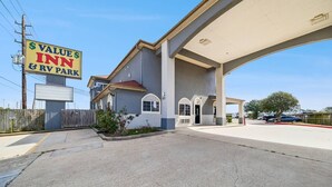 A Value Inn & RV Park with a large parking area, a gas station canopy, and a building with a garage door. - Value Inn and RV Park (Baytown)