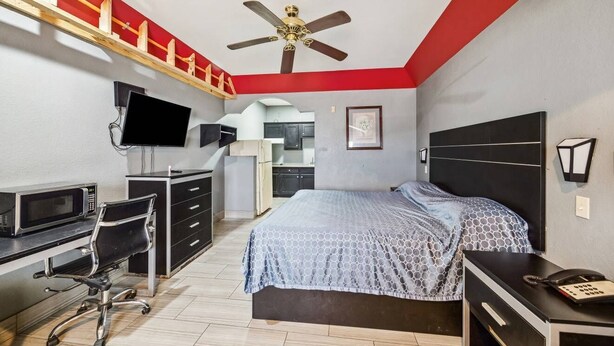 A bedroom with a bed, desk, chair, and a ceiling fan. - Value Inn and RV Park (Baytown)