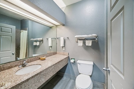 A bathroom with a granite sink, a toilet, a towel rack, and a mirror.. Value Inn and RV Park