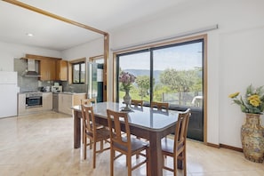 Una cocina moderna con comedor, ventanas amplias y vistas al exterior.