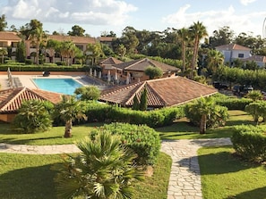 Ein Resort mit Swimmingpool, Palmen und einem gepflasterten Weg.