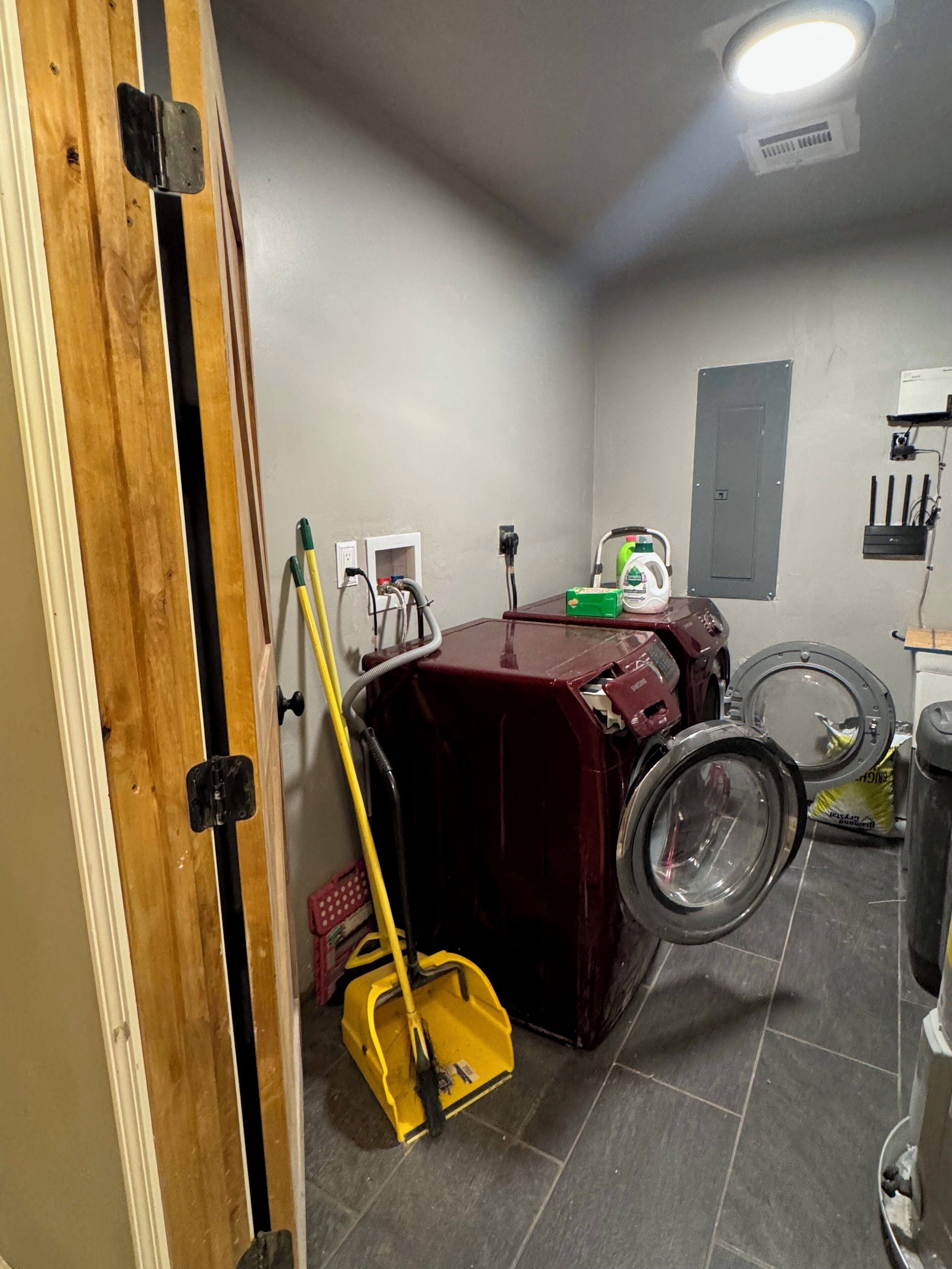 A laundry room with a washing machine, a dryer, a mop, and a broom.