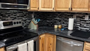 Una cocina con armarios de madera, estufa de acero inoxidable, microondas y lavavajillas.