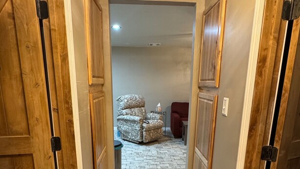 Un pasillo con puertas de madera, un tapete estampado y una silla roja.