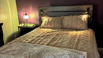 A bed with a quilted cover, a bedside lamp, and a wooden headboard.