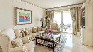 Una sala de estar con un sofá, sillones, una mesa de centro y un cuadro en la pared.