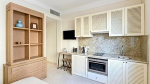 Una cocina compacta con electrodomésticos integrados, un armario de madera y un televisor de pantalla plana.