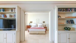 Un dormitorio con cama, mesitas de noche, televisor y estanterías.