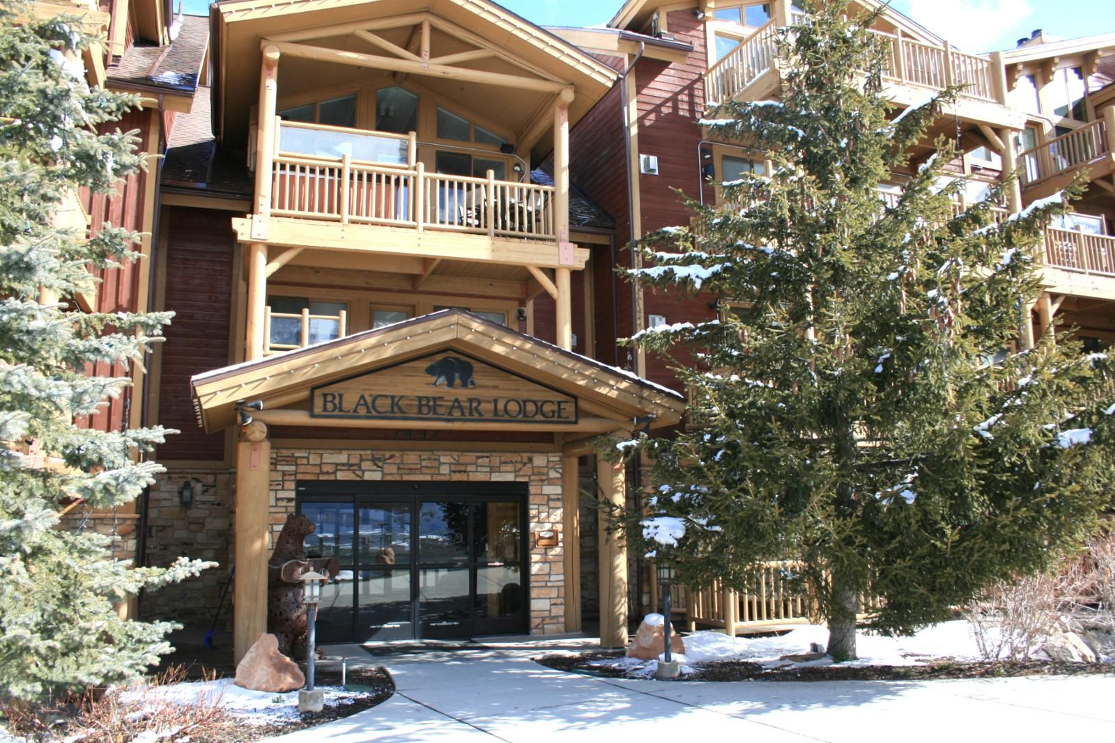 A lodge with a prominent entrance, a balcony, and a sign reading 'BLACK BEAR LODGE.'