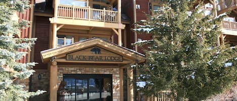 A lodge with a prominent entrance, a balcony, and a sign reading 'BLACK BEAR LODGE.'