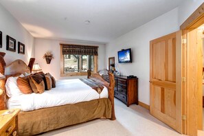 A bedroom with a bed, a dresser, a television, and a large wooden door. - Walk to Ski Slopes + Trails! Cozy 2-Bedroom, 3-Bath, Recently Renovated Condo with Pool, Hot Tub, BBQ, and A/C | BBL-251 by KBM Resorts (Park City)