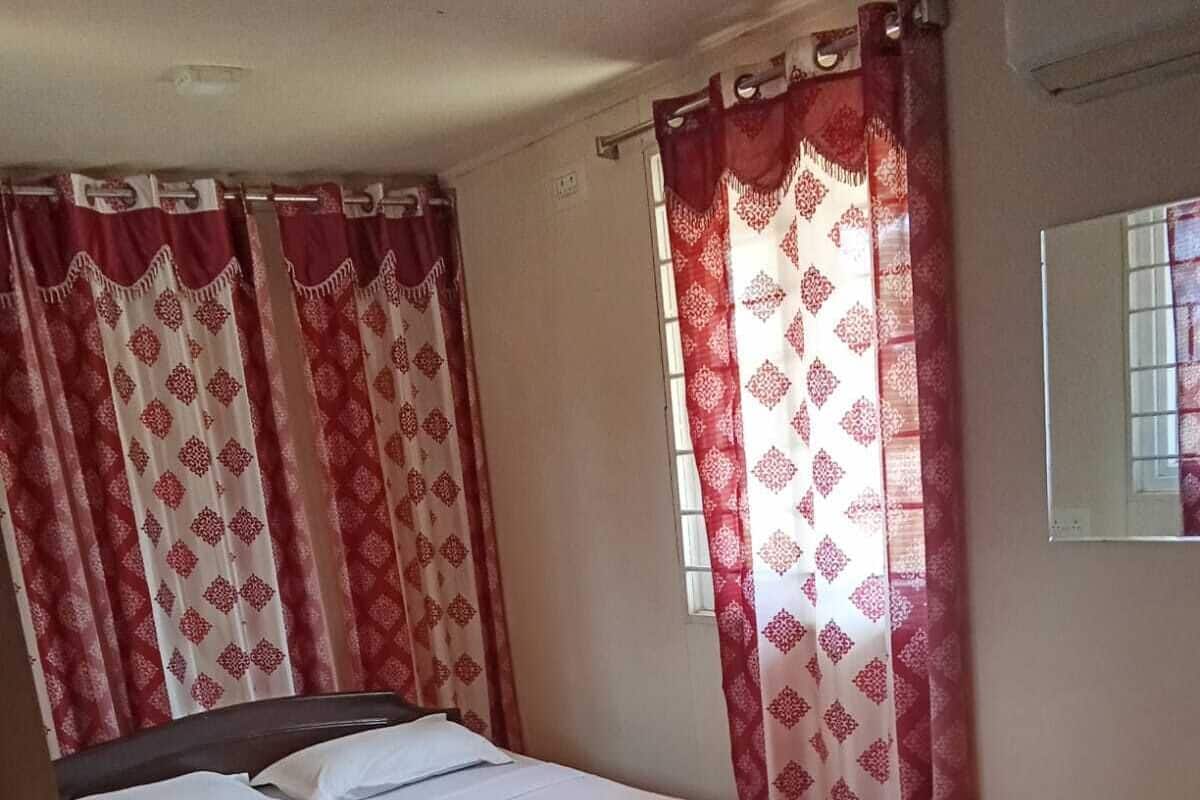 Un dormitorio con cama, cortinas y una ventana.
