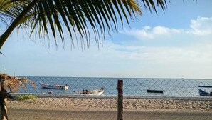 Una playa con una cerca, barcos y una palmera.