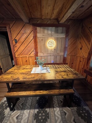 A wooden table with a neon sign, a vase with flowers, and a plaid placemat. - FUN! Log Cabin Hot Tub & Game Room w Pool Table Pets OK 3BR/2BA Sleeps 10 (Red Oak)