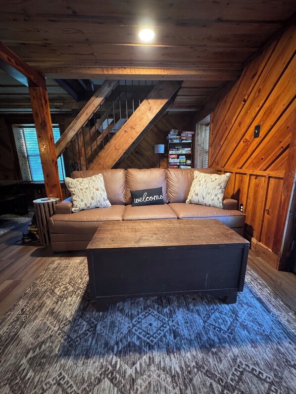 Un intérieur en bois comprenant un ensemble de canapés, une table basse et un tapis à motifs.