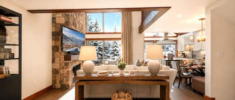 Spacious lodge-inspired interior featuring stone fireplace, mountain views, and stylish dining area.