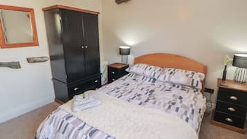 A bedroom with a bed, a wardrobe, a nightstand, a lamp, and a mirror.