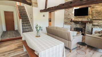 A cozy living room with a sofa, a table with a bench, a fireplace, and a staircase.