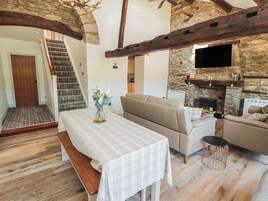 Una sala de estar acogedora con un sofá, una mesa con un banco, una chimenea y una escalera.