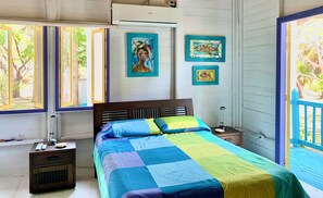 Un dormitorio con cama, mesitas de noche, lámpara y cuadros en la pared.
