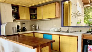 A kitchen with yellow cabinets, a wooden countertop, a built-in oven, and a sink.