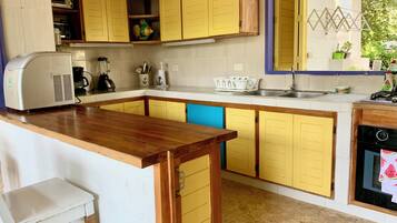 A kitchen with yellow cabinets, a wooden countertop, a built-in oven, and a sink.