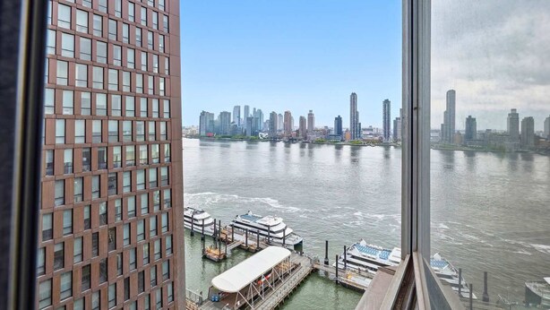 A high-rise building with a view of a river and a city skyline. - Spacious Apt in Murray Hill (New York, NY)